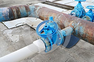 Big blue tap or faucet with removed valve on old rusty water pipe on industrial background