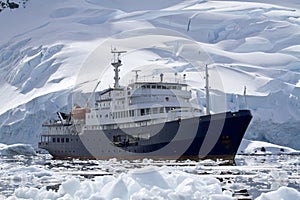 Big blue tourist ship in Antarctic waters against the backdrop o