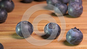 Big blueberries fall and bounce on wooden surface