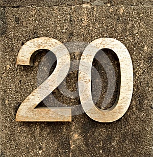 Big bold number 20, twenty, in large metallic digits isolated on gray stone background.