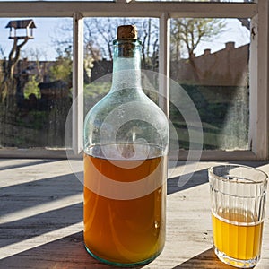 Big bottle with a drink made from fermented birch sap on the windowsill on a warm spring day, closeup. Traditional Ukrainian cold