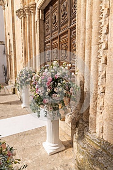 Big bouquets of colorful flowers. Luxury wedding floral decorations at the entrance of Ostuni church.