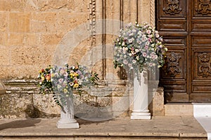 Big bouquets of colorful flowers. Luxury wedding floral decorations at the entrance of Ostuni church.