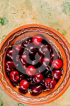 Big bowl with many large red juicy tasty sweet cherries.Fresh cherries berries in bowl on green rustic wooden background