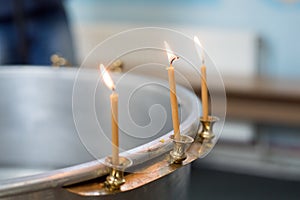 Big bowl of water for the baptism of a baby with wax candles. Orthodoxy. Greek Catholics. macro