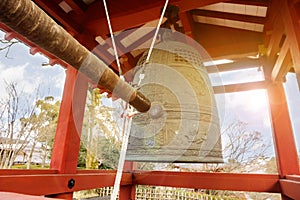 Big brass Buddhist bell and knock bell timber of Japanese temple in red pavilion on bright blue sky