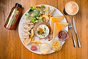 Big breakfast plate with sausage, scrambled eggs, baked beans, bacon, mushrooms and other condiments