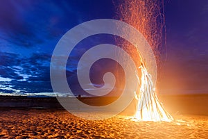 Big bright bonfire on sandy beach at night