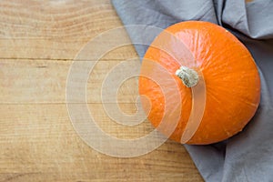 Big Bright Orange Pumpkin Grey Linen Towel on Aged Wood Background. Copy Space for Text. Thanksgiving Harvest Autumn Fall