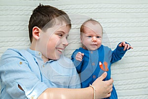 Big brother hugging his newborn baby girl. Toddler kid meeting new sibling