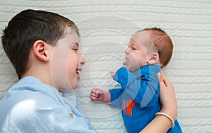 Big brother hugging his newborn baby girl. Toddler kid meeting new sibling