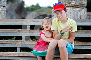 Big brother sitting together with his little sister outdoors