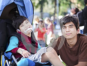 Big brother taking care of disabled brother in wheelchair