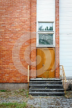 Big brown door on a red brick and white planks wall