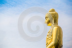 The big Buddha statue against cloudy and blue sky background.