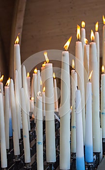 Big burning candles from prayers for hope. Saint Bernadette grotto with many white candles with flame. Sanctuary in Lourdes.