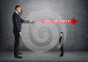 Big businessman poiting at red arrow with 'you're fired'