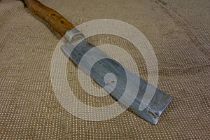 Big butcher knife on bagging fabric background. Closeup view of weapon or utensils with long blade and handle like machete,
