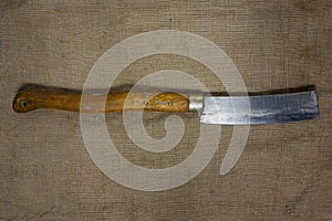 Big butcher knife on bagging fabric background. Closeup view of weapon or utensils with long blade and handle like machete,