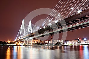 Big cable-stayed bridge over the river at night with colorful bright lighting