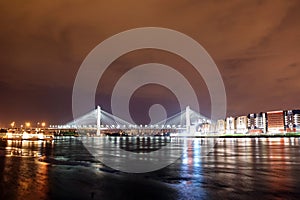 Big cable-stayed bridge over the river at night with colorful bright lighting