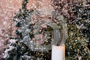 Big candles in glass vases near fir-tree with flashlights in a s