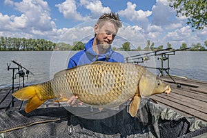 Big carp fishing. Fisherman with huge fish trophy in hands at lake