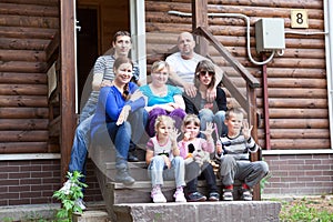 Big Caucasian family with children sitting on the house porch