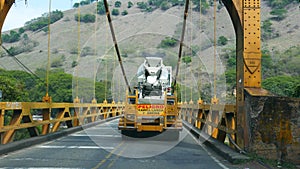 Big cement truck going through a suspension bridge in a road in