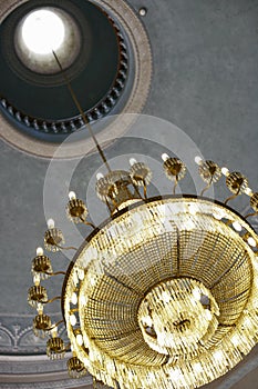 Big chandalier with lights hanging from a hole in the ceiling