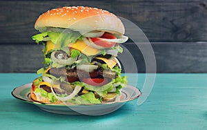 Big cheeseburger deluxe high on green wooden background