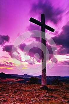 Big Christian cross standing on top of a hill Radobyl in CHKO Ceske Stredohori area at evening after sunset in czech summer land