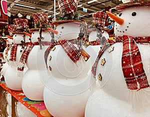 Big christmas snowman with red scarf and hat standing at the hat`s retail shop. Group of snowmen