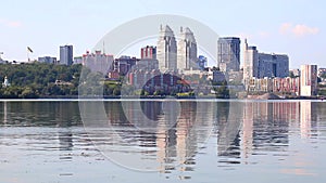 Big city on the banks wide river. Beautiful modern towers, buildings, skyscrapers are reflected in the water on summer