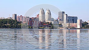 Big city on the banks wide river. Beautiful modern towers, buildings, skyscrapers are reflected in the water on summer