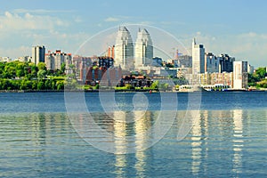 Big city near the river. Beautiful towers, buildings and skyscrapers are reflected in the water of the Dnieper River in