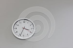 Big clock hanging on grey wall. Classic round wall clock on the grey background. Round clock on office wall