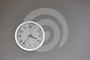 Big clock hanging on grey wall. Classic round wall clock on the grey background. Round clock on office wall