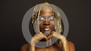 Big close-up portrait of surreal mysterious black african american female model with golden faceart and big glossy lips