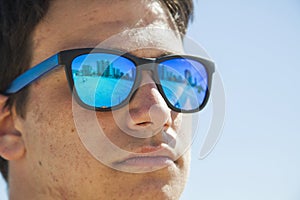 Big Close up portrait of a teenager boy wearing blue mirror sun