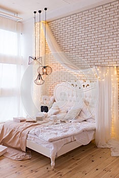 Big comfortable double royal bed in elegant classic interior against a textured white brick wall