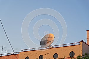 Big communication satellite dish on the roof of an old industrial building