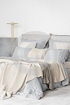 Big and cozy bed with blue and beige bedclothes