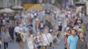 A big crowd of people walking down the street. Out of focus