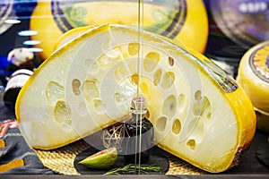 Big cut head of cheese close up on showcase on counter at store, real scene in food market