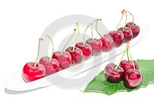 Big dark red ripe cherry berry row arranged on long white dish