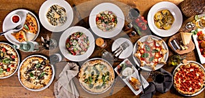 Big dinner table with italian food, pizzas and pastas photo