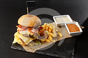 Big double cheeseburger with french fries isolated on black background. hamburger with beef patty , bacon, onion, tomato, lettuce