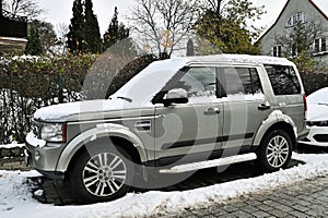Big classic silver grey British 4WD car Landrover Discovery LR3 third generation covered with white snow