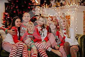 Big family in Christmas pyjamas sitting together on a sofa against Christmas background
